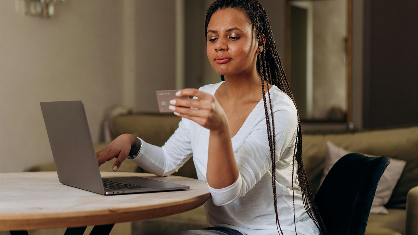 Woman with laptop, looking at her credit card