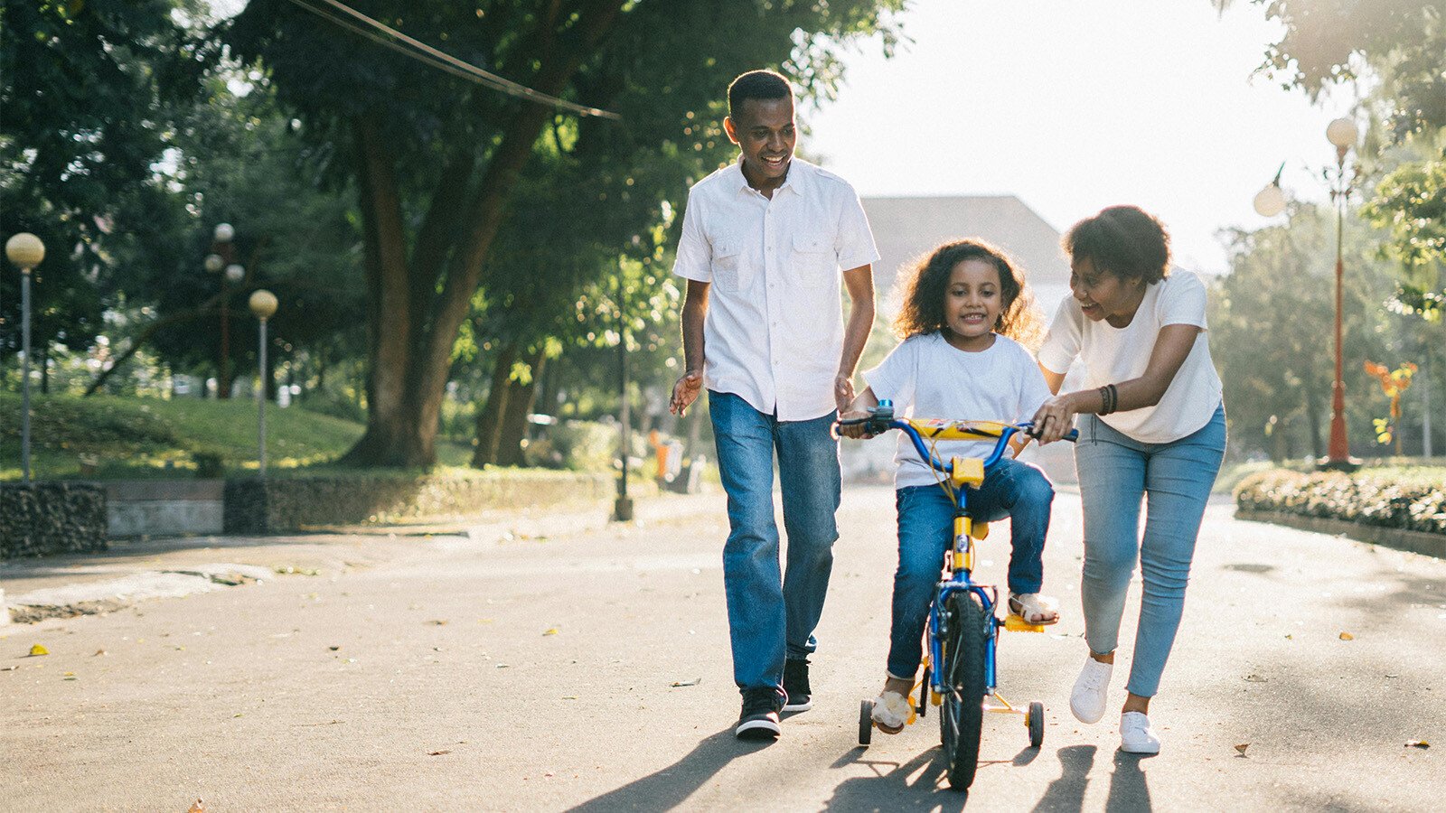 Parents teaching child to ride a bike