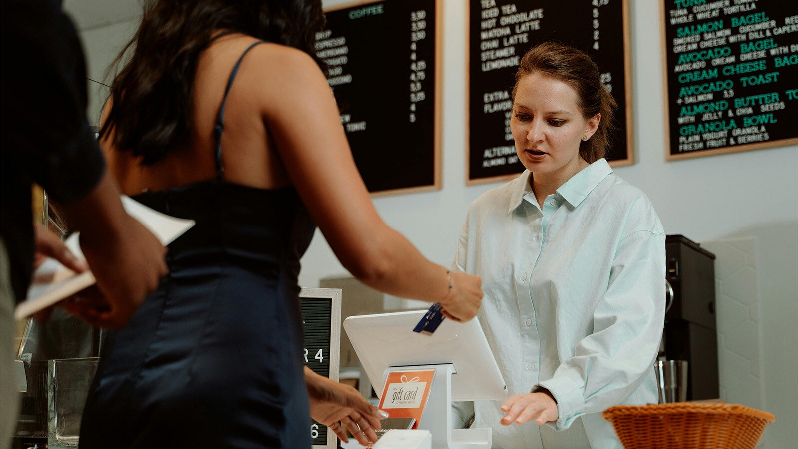 Woman using debit card at a cafe. 